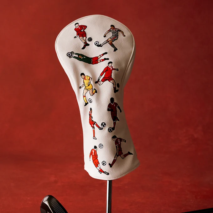 Liverpool FC golf headcover in cream with embroidered footballer illustrations, displayed upright on a club against a textured red background.