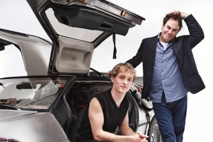 Two actors sit in a silver car