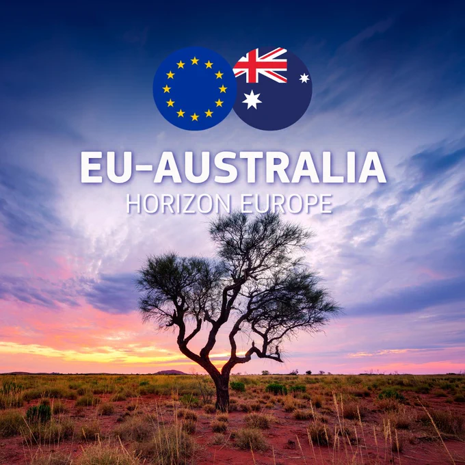 An image featuring a dramatic sunset over an Australian outback landscape with a single, silhouette-like tree in the center. The ground is reddish dirt with sparse, dry grass. The sky transitions from orange near the horizon to deep blue above, filled with soft clouds. At the top center, two circular icons representing the European Union and Australian flags are intertwined, positioned above the bold white text "EU-AUSTRALIA" and the smaller subtitle "HORIZON EUROPE". 