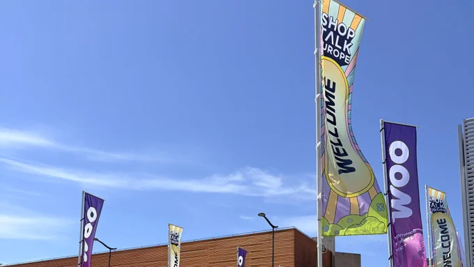 Flags with the Woo logo outside the entrance of Shoptalk Europe. 