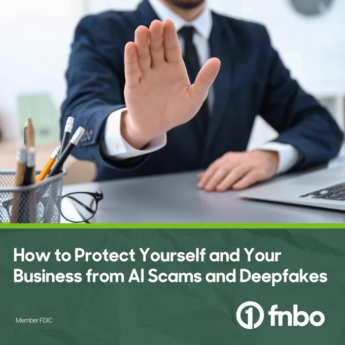 A person in a suit raises their hand in a stop gesture, sitting at a desk with pens, a notebook, and a laptop. Text reads, "How to Protect Yourself and Your Business from AI Scams and Deepfakes." FNBO logo displayed.