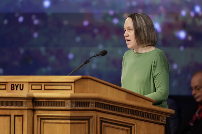 Dr. Jennifer Brooks speaks into a mic at a podium at BYU Devotional, June 2026