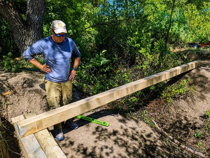 Jeff Davis, DPG trails manager, examines the ground at the bridge site to determine whether it is level. Forest Service photo by Scott C. Marvin