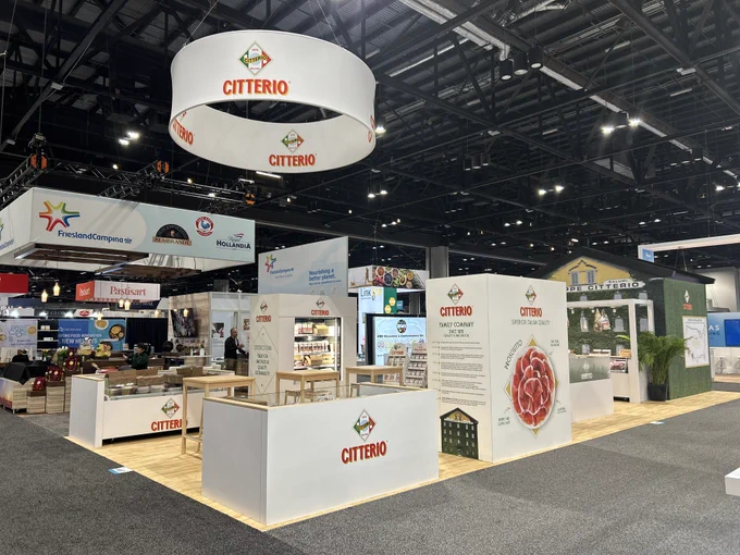 A well-organized trade show booth featuring Citterio branding and products. It showcases various refrigerated Italian meats with informational displays.