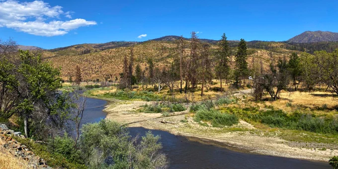 The Klamath River following the 2022 McKinney Fire, with burned areas visible along the distant ridgeline and a debris fan in the foreground near the confluence of Little Humbug Creek and the Klamath River. The photo documents sediment and debris deposited from burned landscapes into the river corridor following wildfire and storm runoff. Photo by Jennifer Curtis, USGS