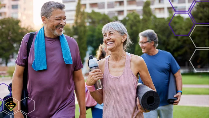 Group of mature adults walking outdoors after exercise, carrying yoga mats and water bottles in a park setting.