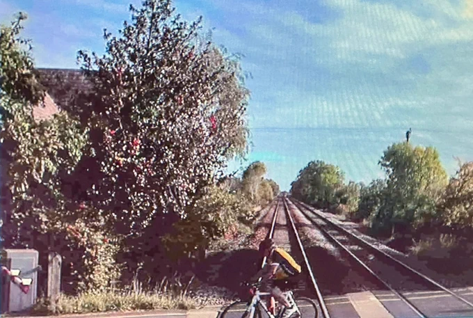The front facing CCTV from an LNER train showing a bike on a level crossing when the gates are clearly down.