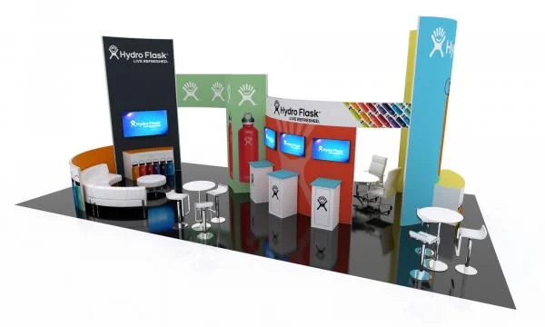3D rendering of a custom Hydro Flask trade show booth featuring tall branded towers, illuminated graphic walls, product displays, digital screens, reception counters, lounge seating, and meeting areas arranged in an open island layout designed for attendee engagement and product showcasing.