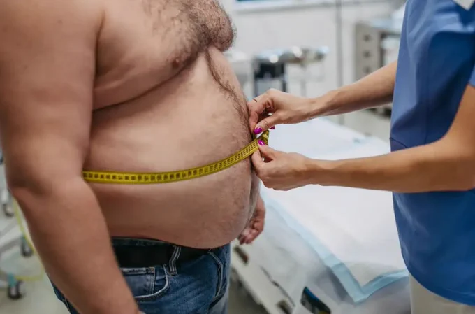 A nurse measuring a man's chest who appears to be overweight