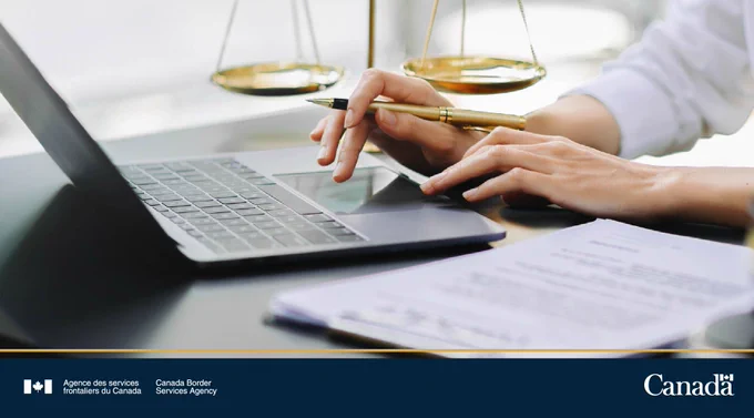 Personne utilisant un ordinateur portable et tenant un stylo avec des balances de justice en arrière-plan sur un bureau avec des documents.
