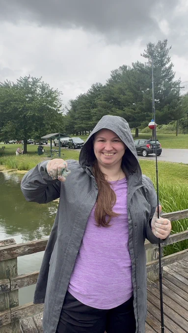 A woman shows off the small fish she just caught.