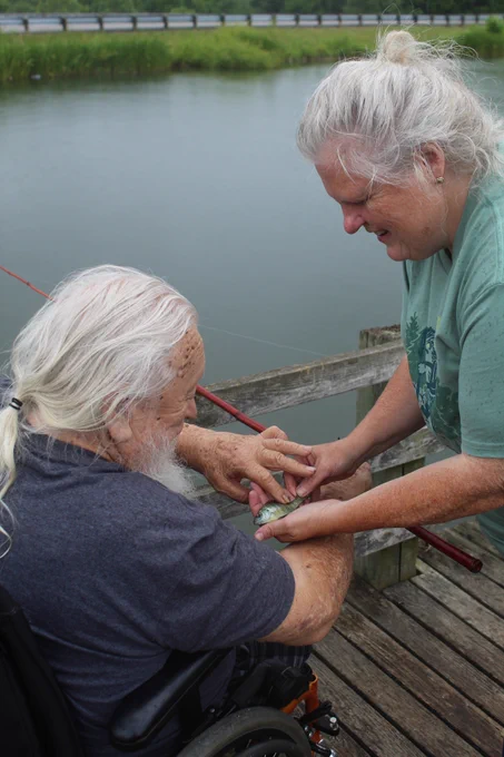 A woman shows her father the small fish they just caught.