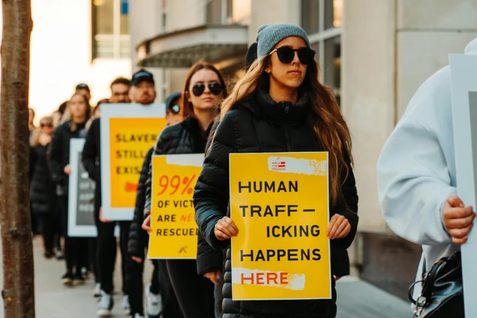 A group of individuals walking in a line during a protest, holding signs with messages against human trafficking. 

Photo credit: Hermes Rivera via Unsplash

