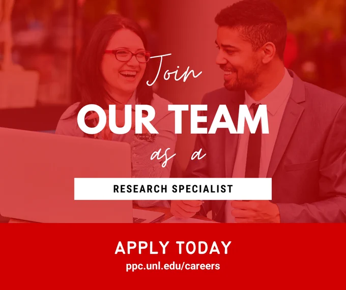 Two professionals in business attire discussing work over a laptop with a call to join the team as a research specialist.