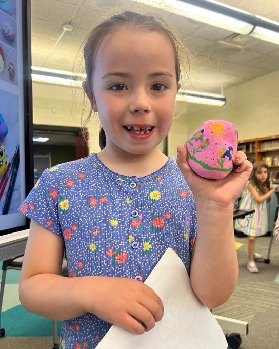 Girl holds a painted pink rock.