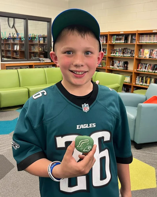 Student holds a handpainted rock for a rock garden.
