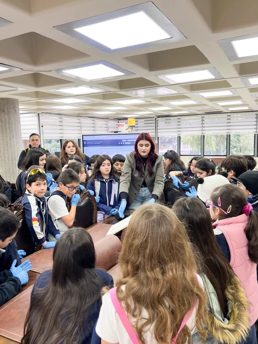 Integrante del equipo de Sala Chle muestra libro patrimonial a escolares durante visita a Biblioteca Central UdeC.
