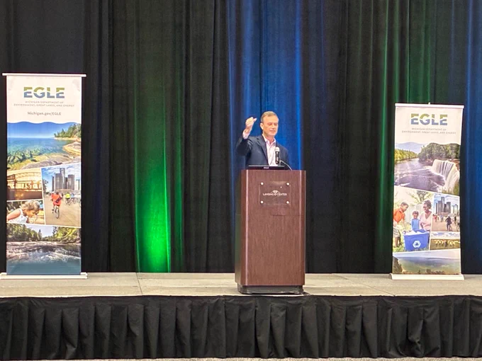 ELGE Director Phil Roos stands at the podium speaking to conference attendees. 