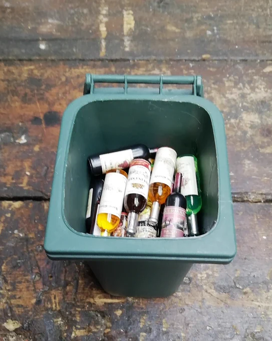 Bin the Booze 1: A grey plastic bin with bottles of liquid of various colours.