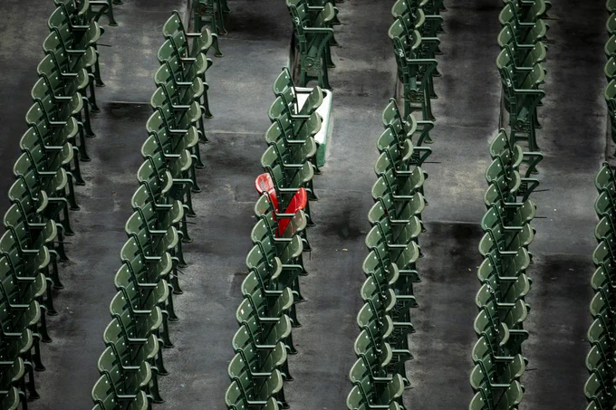 Wide shot of the Fenway Park bleachers where a lone red seat stands out amongst a sea of green seats.