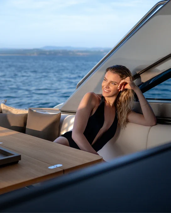 A woman wearing a black swim wear sitting in a deck sofa of a Pershing motor yacht