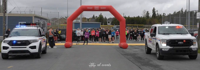 A large group of runners wait near the starting line for the run.