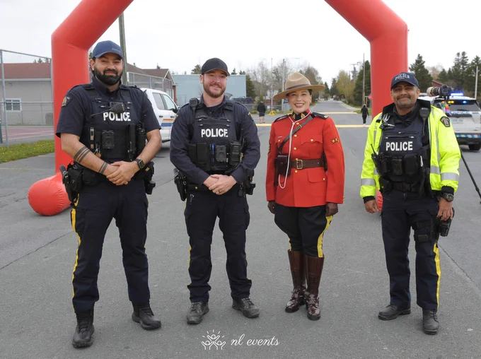 Four RCMP officers stand outside near a roadway.