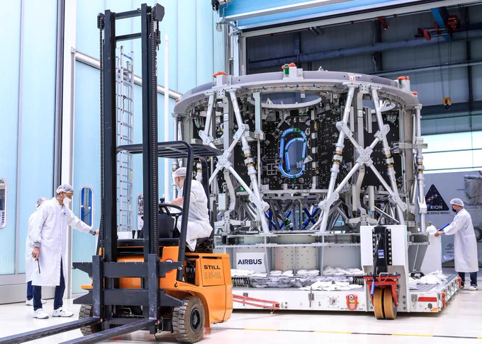 The third European Service Module's structure at Thales Alenia Space in Turin. A grey cylinder in the middle of a cleanroom, with engineers in lab coats.