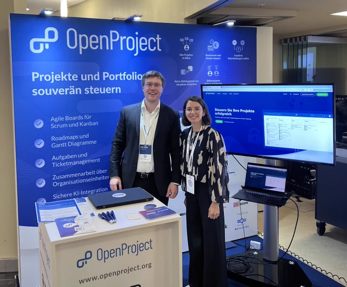 Robin Wagner and Felicia Mundhenke at the OpenProject booth during the Zukunftskongress Staat & Verwaltung 2026 in Berlin. They are presenting OpenProject's open source project and portfolio management platform and engaging with public sector attendees.