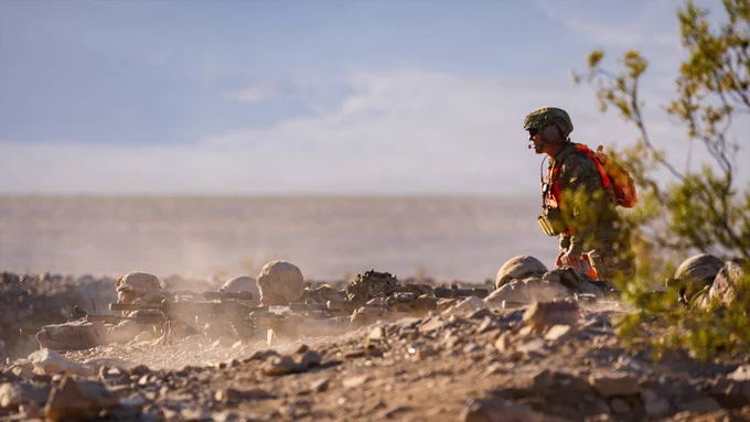 A range safety Marine observes firing positions as Marines engage targets during a live-fire exercise.