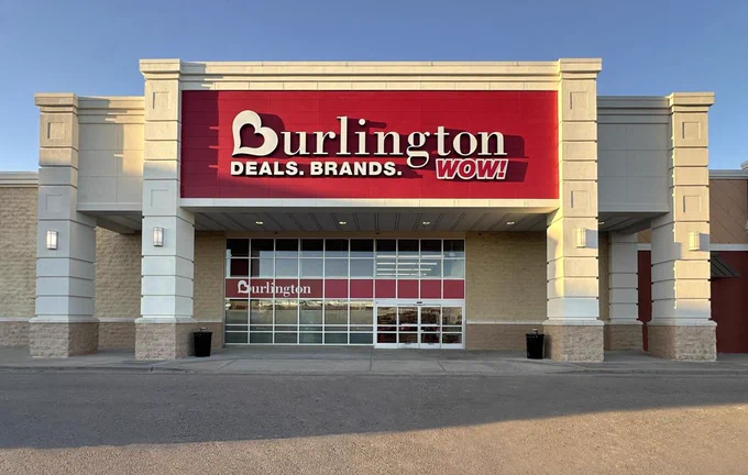The exterior of a Burlington store with the brand's large red sign prominently displayed in the evening light.