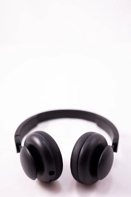 From above of modern shiny black wireless headphones placed on white background in light studio
