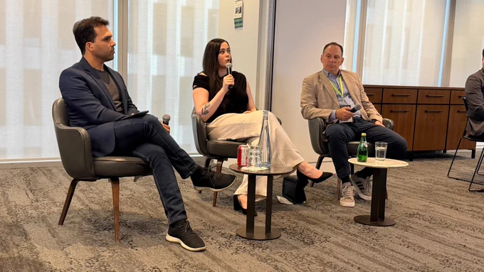  Three people participate in an Investor and Capital panel discussion at the A11yVerse x IAAP Canada Summit. From left to right: Moderator Varun Chandak from Access to Success sits in a chair holding a tablet; Alwar Pillai from Fable speaks into a handheld microphone while seated in the center; David Ceolin from Innovation Grade Ventures sits to the right holding a microphone. Small tables with water glasses and bottles are positioned in front of the panelists, and floor-to-ceiling windows form the backdrop of the conference room. 