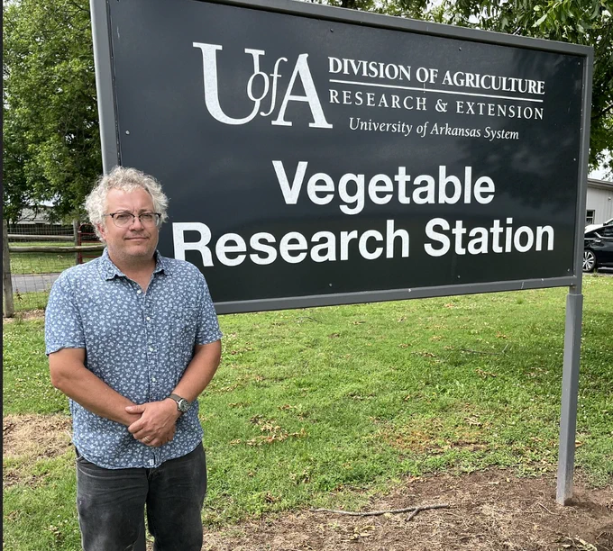 Larry Galligan standing in front of a sign