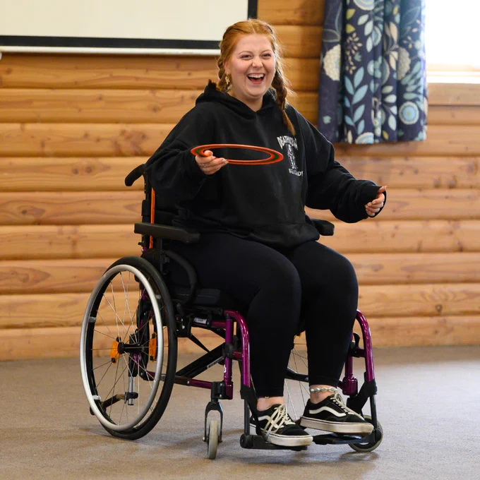 Photo of a young person smiling whilst throwing a Frisbee during a Back Up Youth Advisory Group weekend.
