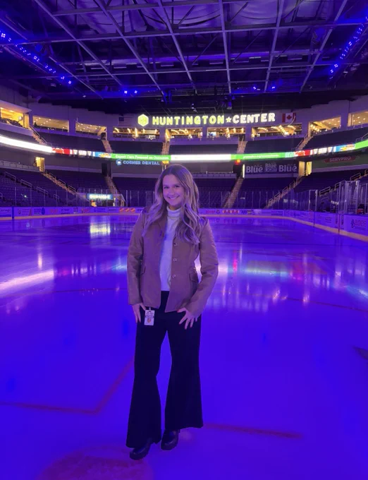 A person stands on an ice rink at Huntington Center. The arena is illuminated with purple lights. The seating areas are empty.