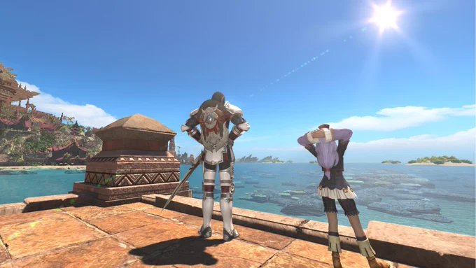 A screenshot from Final Fantasy 14. Prishe and Alxaal are shown from behind standing on a quay in Tuliyollal, looking leisurely out towards to the sea. The sun shines brightly in a blue sky.