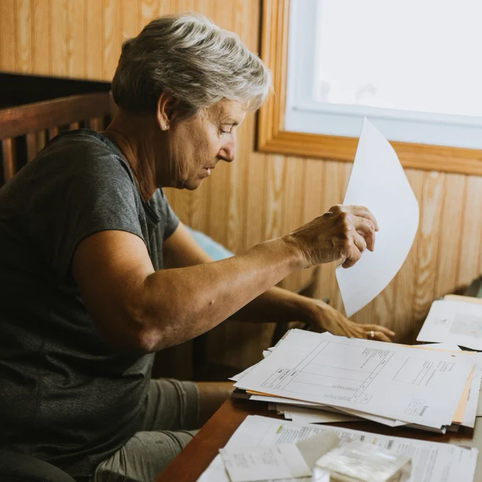 Female farmer reveiws paperwork while working at a desk. 