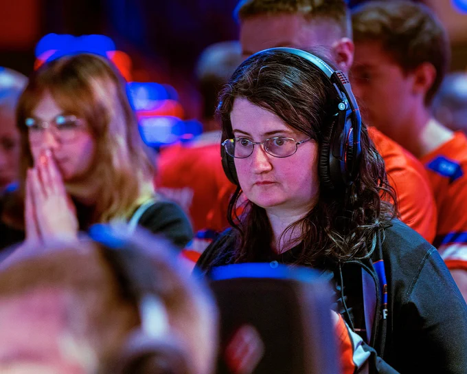 Kelsey Moser, a Boise State economics graduate student and the associate coach for Bronco Esports wearing a headset and watching her team play. 
