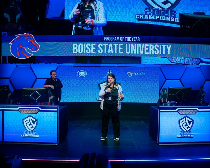 Kelsey Moser, a Boise State economics graduate student and the associate coach for Bronco Esports speaking to a crowd on stage at the PEC 2026 Championship for esports. 
