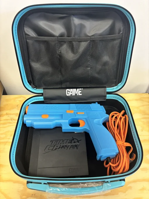 A blue toy gun with orange accents is neatly packed inside a black and blue hard-shell case. The case is labeled 'GAIМЕ' on the inside flap.
