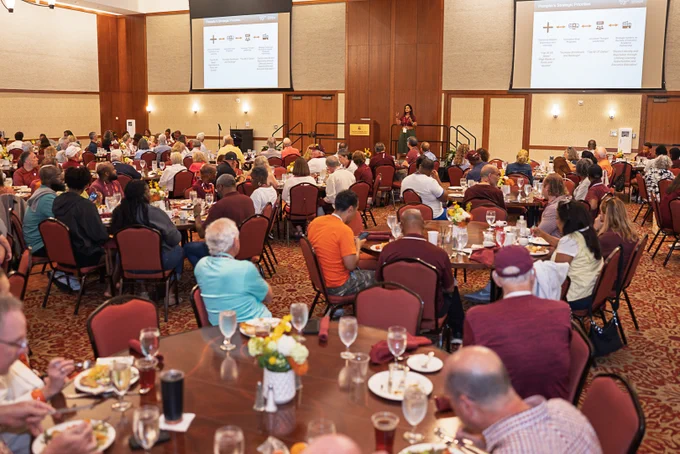 Wide-angle crowd shot of alumni listening to the Dean talk