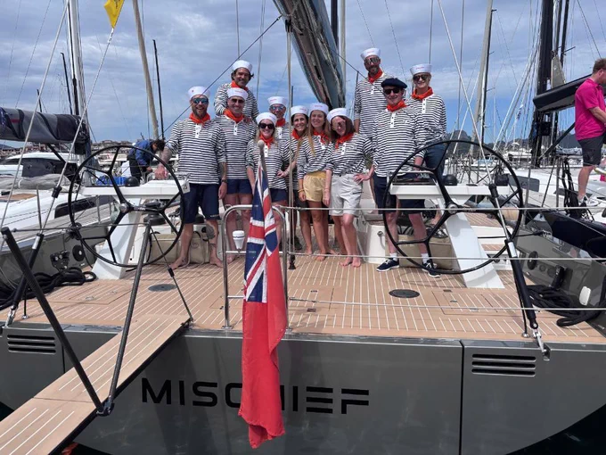 A group of people dressed as sailors stand on the deck of a yacht.