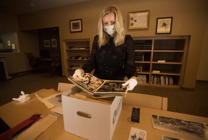 A staff member reviews archival materials from the Fairplex Records collection at Cal Poly Pomona University Library's Special Collections & Archives. Boxes and documents are spread across a worktable during the archival ingest process.