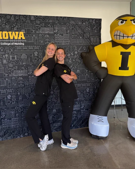 Photo of two College of Nursing students posing in black scrubs.