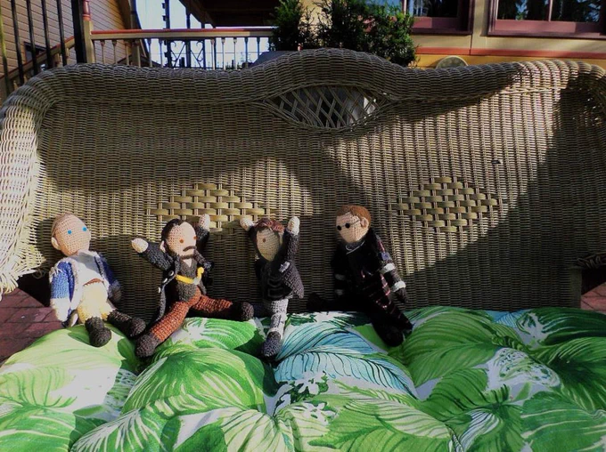Crochet dolls of Benjamin Tallmadge, Caleb Brewster, Adolphus Murtry & Vinsher Grath are seated on the outside beige wicker settee with green palm frond cushion. Caleb & Murtry have their arms raised in argument.  