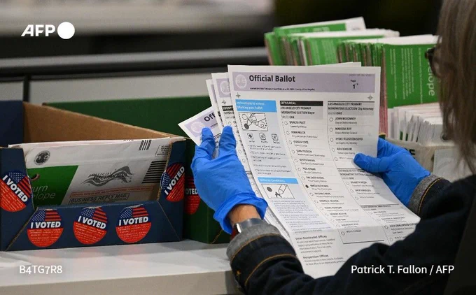 A ballot marked for Karen Bass is processed by an election worker wearing blue gloves during ballot tabulation at the Los Angeles County Ballot Processing Center 