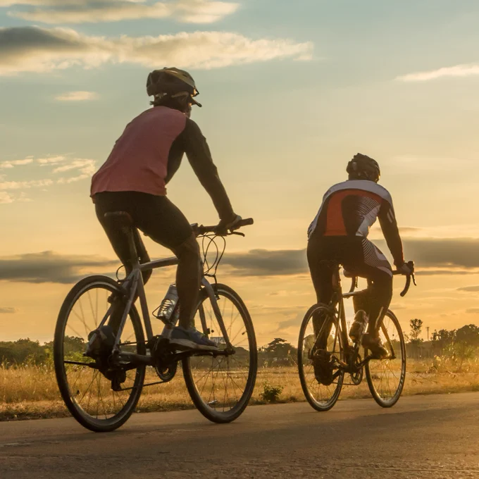 Two cyclists riding into the sunrise.