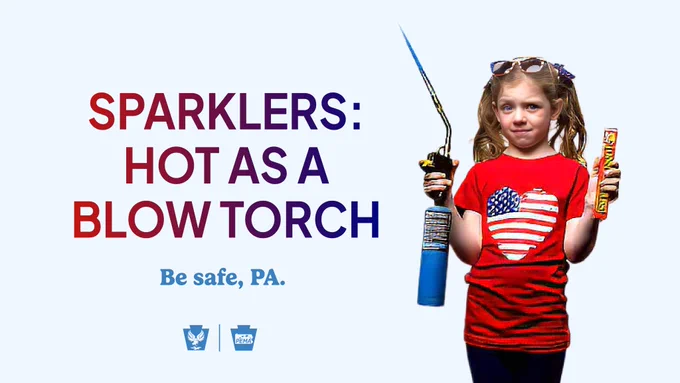 A girl wearing an American flag shirt holds a box of sparklers in one hand and an ignited blow torch in another. Sparklers: Hot as a blow torch. Be safe, PA.