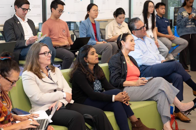 A group of people sitting on a couch and in chairs, looking forward